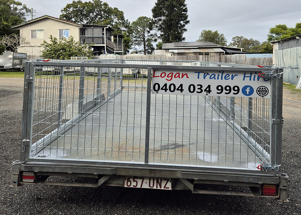 Metal flatbed trailer with a mesh gate and a banner reading 'Logan Trailer Hire' with phone 0404 034 999 and social icons; parked on gravel driveway.